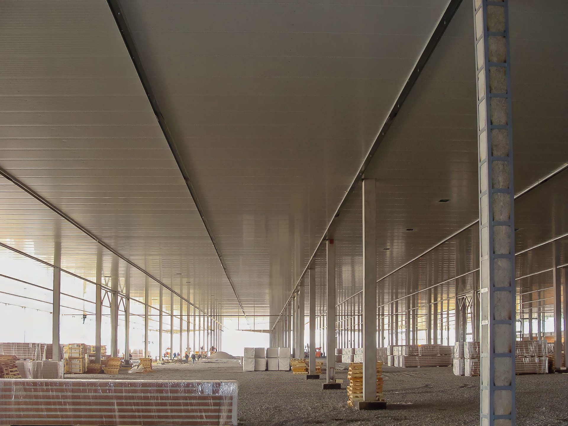 Vista gran angular de un edificio en construcción con vigas metálicas y suelo de grava.