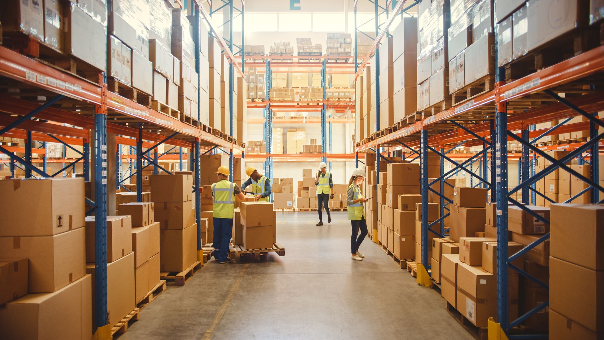 Almacén al por menor lleno de estantes con mercancías en cajas de cartón, paquetes de escaneo y clasificación de trabajadores, inventario de movimiento con camiones de palés y carretillas elevadoras. Centro de entrega de distribución de productos.